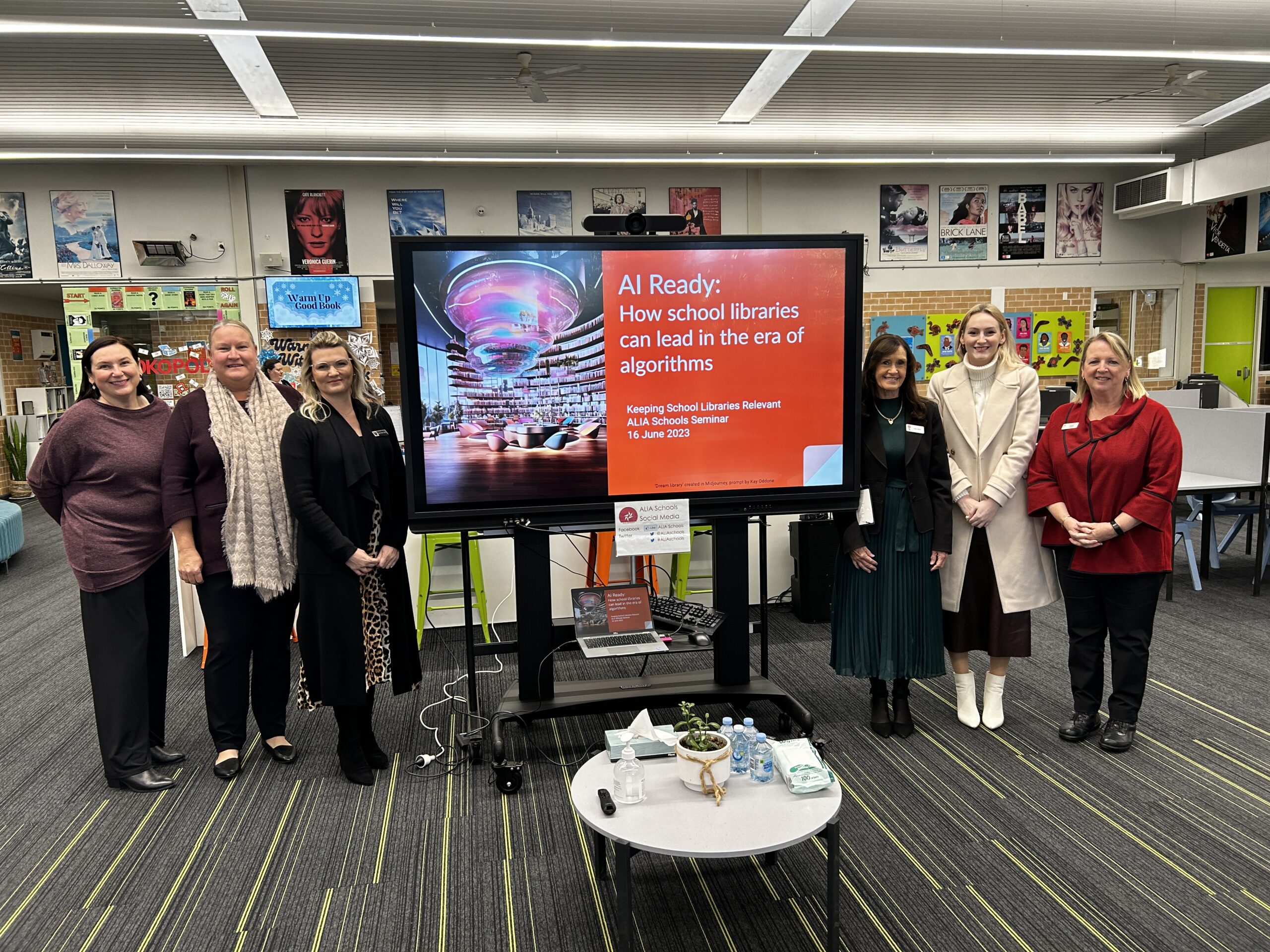 Presenters and staff standing in front of screen with keynote title slide.